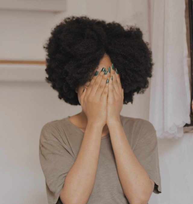 Woman hides her face with the palm of her hands