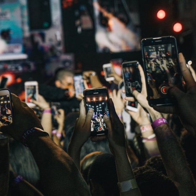 Audience at a music concert pointing their cellphones to the stage