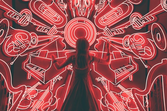 Person stands in front of neon silhouettes of musical instruments